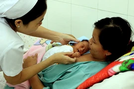 Nhân viên y tế hướng dẫn cách chăm sóc trẻ bằng phương pháp 'da kề da.' (Ảnh: Dương Ngọc/TTXVN)