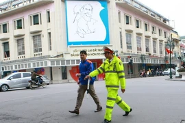 Nhắc nhở người đi bộ không đúng nơi quy định trên phố Hàng Bài-Hàng Khay, Hà Nội. (Ảnh: Doãn Tấn/TTXVN)