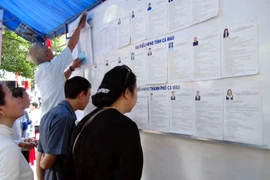Cử tri phường 9, thành phố Cà Mau tìm hiểu danh sách niêm yết tiểu sử từng ứng cử viên trước khi bỏ phiếu bầu. (Ảnh: Kim Há/TTXVN)