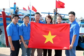 Các đoàn viên tự hào tặng cờ Tổ quốc cho ngư dân. (Ảnh: Nguyễn Thanh/TTXVN) 