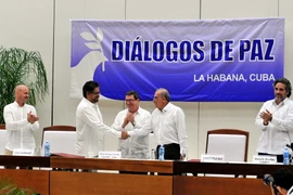 Đại diện của Chính phủ Colombia và FARC bắt tay sau khi được Ngoại trưởng Cuba Bruno Rodríguez (giữa) trao tượng trưng hai phiên bản thỏa thuận. (Ảnh: Lê Hà/TTXVN)