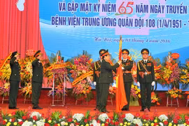 Đại tướng Ngô Xuân Lịch gắn Huân chương Bảo vệ Tổ quốc hạng Nhất lên Cờ truyền thống của Bệnh viện 108. (Ảnh: Trọng Đức/TTXVN)