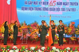 Đại tướng Ngô Xuân Lịch gắn Huân chương Bảo vệ Tổ quốc hạng Nhất lên Cờ truyền thống của Bệnh viện 108. (Ảnh: Trọng Đức/TTXVN)