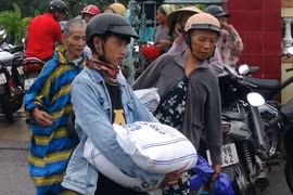Người dân nhận gạo hỗ trợ. (Ảnh: Trịnh Bang Nhiệm/TTXVN)