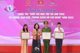 Thứ trưởng Bộ Giáo dục và Đào tạo Ngô Thị Minh trao bằng khen cho các tác giả đạt giải nhất. (Ảnh: Thanh Tùng/TTXVN)