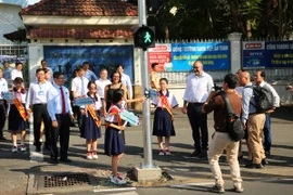 Học sinh trường Trung học cơ sở Lê Quý Đôn sử dụng đèn tín hiệu dành cho người đi bộ tại cổng trường. (Ảnh: PV/Vietnam+)