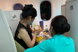 Tiêp viên Vietnam Airlines hỗ trợ chăm sóc sức khỏe hành khách trên một chuyến bay. (Ảnh: PV/Vietnam+)