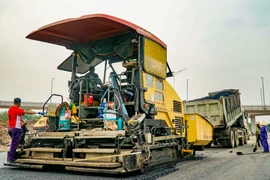 Nhà thầu thi công thảm nhựa nền đường một tuyến Quốc lộ. (Ảnh: Việt Hùng/Vietnam+)