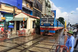Tàu hỏa chạy qua một đường ngang có nhân viên đường sắt chốt trực tại gác chắn. (Ảnh: Việt Hùng/Vietnam+)