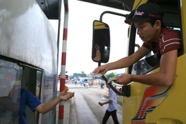 Lái xe dùng tiền mệnh giá 200 - 500 đồng mua vé qua trạm thu phí BOT tuyến tránh Biên Hòa gây ùn tắc kéo dài, ngày 2/10. (Ảnh: Sỹ Tuyên/TTXVN)