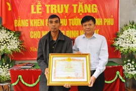 Phó Tổng Giám đốc Thông tấn xã Việt Nam Đinh Đăng Quang thừa ủy quyền của Thủ tướng Chính phủ trao Bằng khen của Thủ tướng Chính phủ cho gia đình cố Nhà báo Đinh Hữu Dư. (Ảnh: Minh Đức/TTXVN)