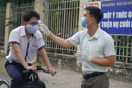 Học sinh Trường THPT Trần Văn Giàu, quận Bình Thạnh được đo thân nhiệt trước khi vào trường. (Ảnh: Xuân Anh/TTXVN)