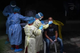 Nhân viên y tế lấy mẫu xét nghiệm COVID-19 cho người lao động nước ngoài tại khu ký túc xá ở Singapore. (Ảnh: AFP/TTXVN)