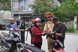 Lực lượng chức năng kiểm tra giấy phép lái xe, đăng ký xe đối với người điều khiển phương tiện xe môtô. (Ảnh: TTXVN phát)