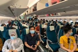 Các công dân Việt Nam trên tàu bay của Vietnam Airlines, chuẩn bị lên đường về nước. (Ảnh: Hà Ngọc/TTXVN)