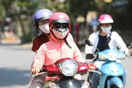 Người dân đeo khẩu trang mặc đồ tránh nắng khi tham gia giao thông. (Ảnh: Thành Đạt/TTXVN)