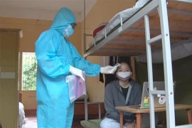 Theo dõi thân nhiệt cho các đối tượng được cách ly. (Ảnh: Đinh Tuấn/TTXVN)