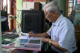 Ông Reo sưu tầm các hình ảnh Bác Hồ. (Ảnh: Hoa Mai/TTXVN)