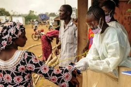 Các nhân viên y tế Liberia kiểm tra thân nhiệt hành khách đi qua khu vực cửa khẩu Jendema. (Nguồn: AFP/TTXVN)