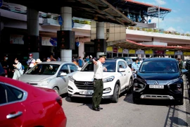 Nhân viên an ninh hàng không Cảng hàng không Quốc tế Nội Bài hướng dẫn, phân luồng xe đi vào sân bay. (Ảnh: PV/Vietnam+)