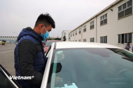 Dán tem kiểm định đối với phương tiện đã được đăng kiểm. (Ảnh: Minh Hiếu/Vietnam+)