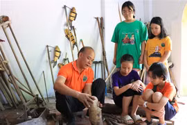 Nghệ nhân Nguyễn Thành Lai, trưởng phường rối nước Luy Lâu, giới thiệu con rối đến với các em học sinh. (Ảnh: Thanh Thương/TTXVN)