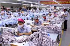Một dây chuyền may gia công sản phẩm quần áo bảo hộ lao động và áo sơ mi xuất khẩu. (Ảnh: Vũ Sinh/TTXVN)