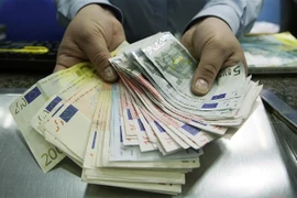 Nhân viên giao dịch ngoại hối kiểm đồng euro. (Ảnh: AFP/TTXVN)