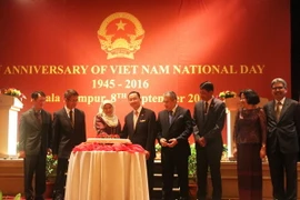 Đại sứ Việt Nam tại Malaysia Phạm Cao Phong và Bộ trưởng Văn phòng Chính phủ Malaysia Hajah Nancy Binti Shukri cắt bánh theo nghi lễ. (Ảnh: Hoàng Nhương/Vietnam+)