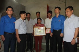 Trao huy hiệu "Tuổi trẻ dũng cảm" tặng em Trần Thị Thu Hà cho đại diện gia đình. (Ảnh: Khiếu Tư/TTXVN)