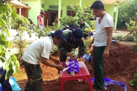 Lực lượng chức năng đang tiến hành cất bốc hài cốt liệt sỹ. (Ảnh: Trần Tĩnh/TTXVN)