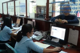 Người dân làm thủ tục tại Văn phòng một cửa. (Ảnh: Đức Thọ/TTXVN)