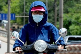 Chị em phụ nữ với những bộ thời trang bịt kín khi tham gia giao thông trên đường phố trong ngày nắng nóng. (Ảnh: Quang Quyết/TTXVN)