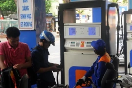 Khách hàng mua xăng tại cửa hàng kinh doanh xăng dầu của Petrolimex. (Ảnh: Quang Quyết/TTXVN)