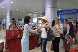 Các du khách Nga nhận món quà chiếc nón lá Việt Nam. (Ảnh: Tiên Minh/TTXVN)
