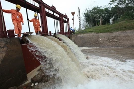 Công nhân Công ty Điện lực Sơn Tây (Tổng công ty Điện lực thành phố Hà Nội) đảm bảo cung cấp điện liên tục, ổn định cho trạm bơm dã chiến Phù Sa. (Ảnh: Ngọc Hà/TTXVN)