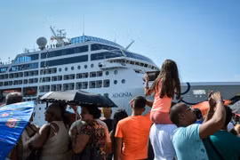 Người dân Cuba chào đón các hành khách trên du thuyền "The Adonia" tại cảng La Habana. (Ảnh: AFP/TTXVN)