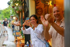 Khách quốc tế thích thú săn ảnh tại 'phố đường tàu' Hà Nội. (Ảnh: Minh Sơn/Vietnam+)