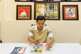 Khưu Tấn Bửu bên tác phẩm tranh gạo. (Ảnh: Ánh Tuyết/TTXVN)