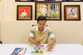 Khưu Tấn Bửu bên tác phẩm tranh gạo. (Ảnh: Ánh Tuyết/TTXVN)