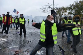 Người biểu tình "áo vàng" quá khích ném đá, bắn súng cao su vào cảnh sát tại Đại lộ Champs Elysees ở Paris. (Ảnh: AFP/TTXVN)