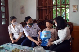Thượng tá Nguyễn Văn Hiển - Phó Chính uỷ Vùng Cảnh sát biển 1 - tặng quà cho Mẹ Việt Nam Anh hùng Nguyễn Thị Cẩm, 94 tuổi, có hai con liệt sỹ tại khu 5, thị trấn Tiên Lãng, Hải Phòng. (Ảnh: TTXVN)