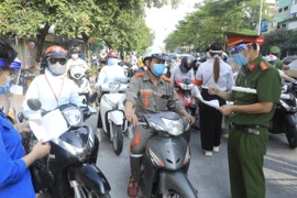 Lực lượng chức năng kiểm tra giấy tờ tùy thân và xác nhận đi làm, ra ngoài của cơ quan với người dân lưu thông trên đường Đào Tấn, Hà Nội, sáng 28/7. (Ảnh: Lâm Khánh/TTXVN)