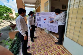 Lãnh đạo Ủy ban Nhân dân tỉnh Tiền Giang và Sở Giáo dục và Đào tạo kiểm tra sơ đồ bố trí các phòng thi. (Ảnh: Hữu Chí/TTXVN)