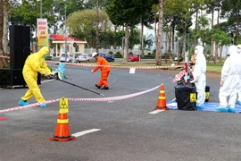 Lực lượng chống nhiễm bẩn phóng xạ (áo màu vàng) tiến hành xác định vị trí, nhận diện và đánh giá tình trạng nhiễm bẩn của nguồn phóng xạ trong khu vực hàng rào khoanh vùng. (Ảnh: Thu Hiền/TTXVN)