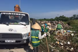 Công nhân Công ty Một thành viên Môi trường đô thị Hà Nội thu dọn rác thải bị đổ trộm tại Đại lộ Thăng Long. (Ảnh: Mạnh Khánh/TTXVN)