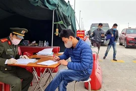 Lực lượng chức năng làm nhiệm vụ hướng dẫn, phân luồng giao thông, khai báo y tế tại chốt trạm cầu Bạch Đằng, thị xã Quảng Yên. (Ảnh: TTXVN)