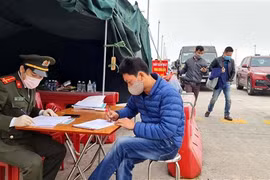 Lực lượng chức năng làm nhiệm vụ hướng dẫn, phân luồng giao thông, khai báo y tế tại chốt trạm cầu Bạch Đằng, thị xã Quảng Yên. (Ảnh: TTXVN)