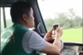 Tài xế hãng xe buýt Khanh Quỳnh vừa lái xe vừa lướt điện thoại. (Ảnh: TTXVN phát)