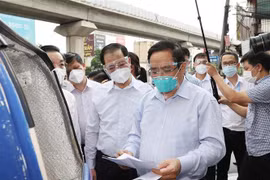 Thủ tướng Phạm Minh Chính kiểm tra đột xuất giấy phép đi đường và các biện pháp phòng dịch của một nhân viên giao hàng trên địa bàn quận Thanh Xuân (Hà Nội), chiều 31/8/2021. (Ảnh: Dương Giang/TTXVN)